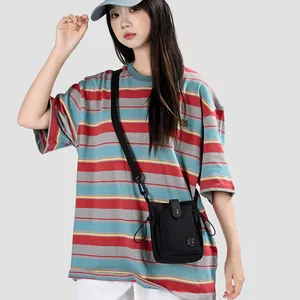 Vue détaillée d'un petit sac bandoulière noir en nylon pour téléphone porté par un mannequin.