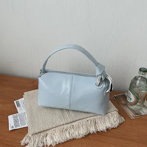 Detail view of a light blue pillow bag with silver hardware on a wooden table setup.