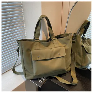 Detailed close-up of a large olive green canvas tote bag featuring a front pocket