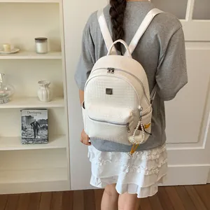 Elegante zaino intrecciato bianco da donna indossato da una modella in un interno