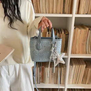 Detailed view of light blue denim bucket bag with silver studs and star charm