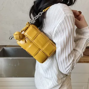 Close-up detail of a yellow woven armpit bag with silver chain strap worn by a model