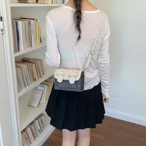 Elegant contrast color small square bag shown as a crossbody accessory on a model