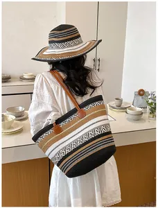 Modisches Model mit einer großen gestreiften Strohtasche und passendem Sonnenhut.