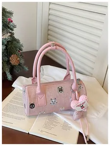 Pink barrel handbag with cartoon patches and plush heart charm on a lifestyle background.