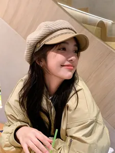 Side view of a vintage beige plaid newsboy hat worn by a smiling model in a cafe setting