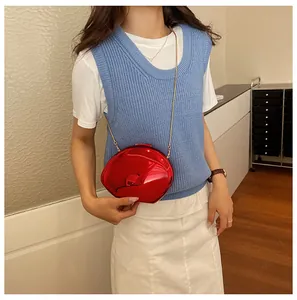 Dettaglio della borsa a specchio rossa con catena d'oro indossata su gilet in maglia