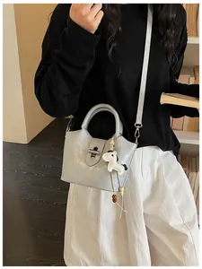 Sac seau design minimaliste bleu clair avec breloque cheval porté par modèle en bibliothèque