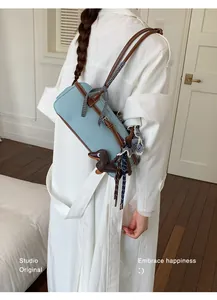 Side view of a light blue Boston shoulder bag worn by a model in a minimal room