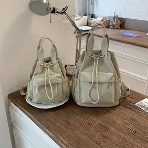 Comparación de dos tamaños de mochilas minimalistas de color caqui con cordón en mesa