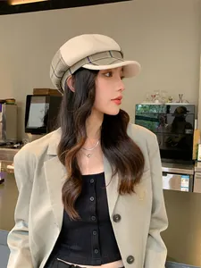 Asiatische Frau trägt eine modische Retro-Karo-Oktogonal-Mütze in einem Café-Ambiente