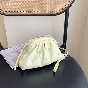 Detail of light yellow pleated cloud bag with blue polka dots on a stylish chair