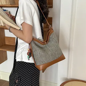 Detailed view of a large woven commuter shoulder bag worn by a model in a library setting
