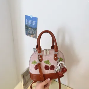 Detalle de bolso rosa de diseño de nicho con bordado de cerezas y amuleto de perlas