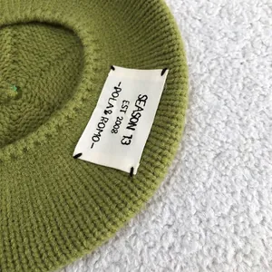 Close-up of a green knitted beret featuring a stylish white POLA & ROMO letter patch.