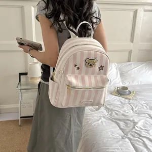 Lifestyle view of a model wearing a pink and white striped backpack with a bear motif