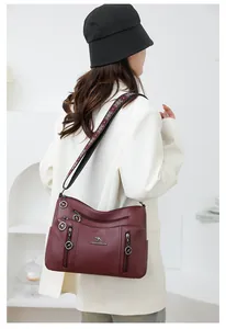 Back view of a burgundy multi-pocket crossbody bag with patterned strap on model