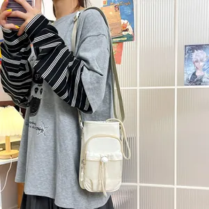 Detalle de un bolso bandolera de nailon crema para móvil femenino en una modelo