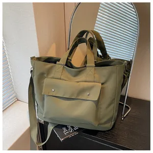 Detailed view of the large capacity green canvas tote bag with front flap and strap