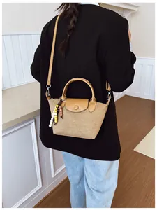 Vue arrière d'une femme portant un sac à main en daim camel avec un charme perlé