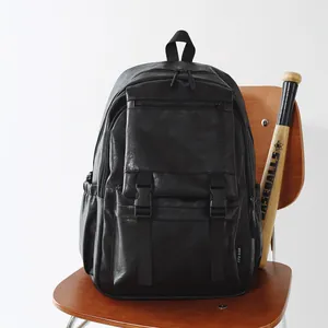 Sac à dos vintage en similicuir noir sur une chaise en bois avec une batte de baseball