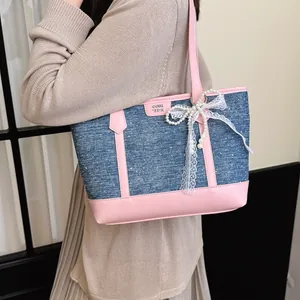 Détail d'un sac cabas en denim avec garniture en cuir rose et noeud en dentelle perlée