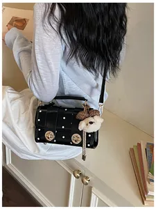 Macro view of a retro black polka dot crossbody handbag with cute teddy bear bag charm