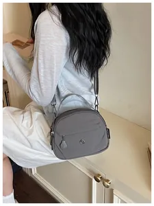 Detalle de un bolso bandolera gris de nailon para el uso diario de mujer.