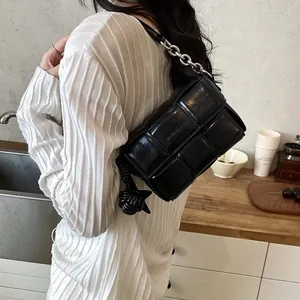 Close-up of black woven leather shoulder bag with thick chain detail on a model