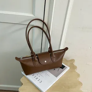 Sac à main marron minimaliste de style dumpling sur un magazine, vue détaillée lifestyle.