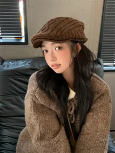 Model wearing a stylish brown cable-knit retro flat cap in a cozy indoor setting.