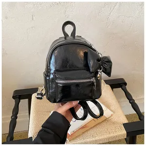 Detailansicht eines glänzenden schwarzen Mini-Rucksacks mit modischer Schleife