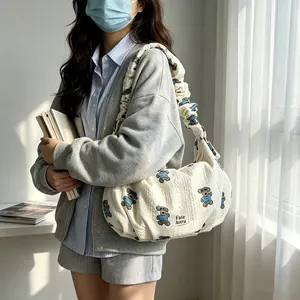 Stylish white dumpling shoulder bag with a cute bear pattern and ruffled strap decor