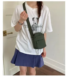 Stylish olive green mini crossbody square bag for women worn by a model in a casual setting
