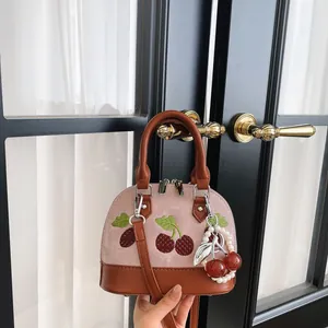 Detalle de cerca del mini bolso bandolera rosa con bordado de cerezas y colgante de perlas