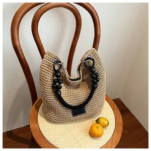 Close-up of a stylish hand-woven straw bucket bag with elegant black bead handles