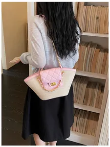 Détail d'une femme portant un sac en paille tressée rose matelassé avec chaîne
