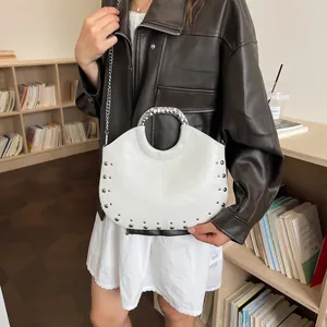 Detailed view of chic white hobo handbag featuring silver studs and metal ring handle