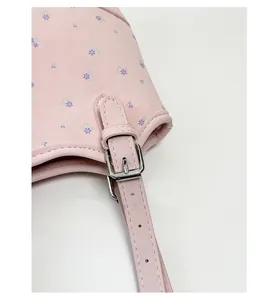Close-up detail of silver metal buckle and strap on a pink floral printed leather handbag