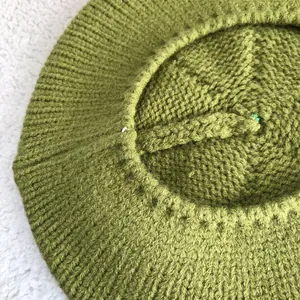 Detailed close-up showing the fine knitted texture of a stylish green wool beret artist hat