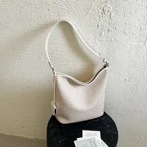 Detailopname van de beige geweven leertextuur van een elegante retro stijl bucket bag