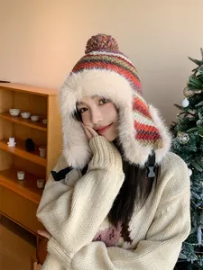 Asian woman wearing a stylish knit trapper hat with fluffy faux fur trim in a cozy setting