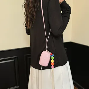 Back view of a pink mini crossbody square bag worn over a black long sleeve top