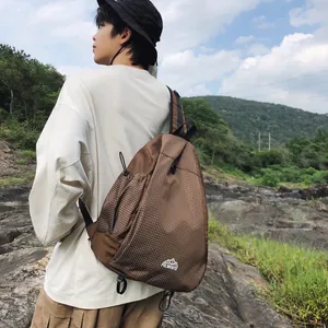 Uomo che indossa una borsa a tracolla marrone a griglia durante un'escursione all'aperto