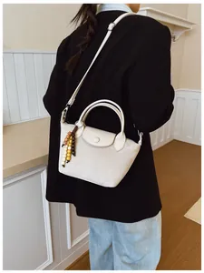 Sac bandoulière femme beige style dumpling avec breloque en perles et tenue de mannequin.