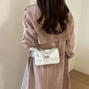 White quilted crossbody bag with lace charm detail on a stylish model