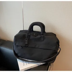 Sac de voyage noir haut de gamme à grande capacité posé sur un accessoire de livre