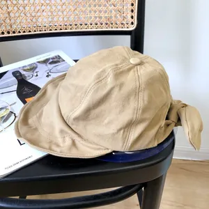 Vista detallada de un sombrero de sol beige de ala ancha con lazo decorativo en la parte posterior