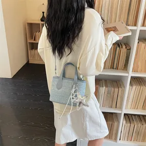 Model carrying a light blue studded small handbag with a star charm in a library setting.