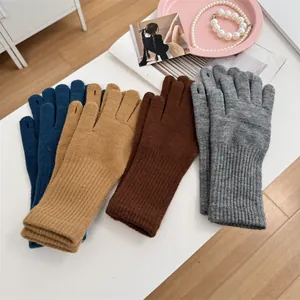 Detailed view of knitted winter warm gloves in various colors on a white table